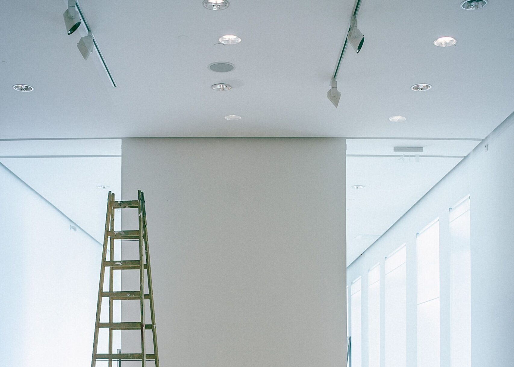 Interior of empty spacious hallway with white walls and ladder for installation works