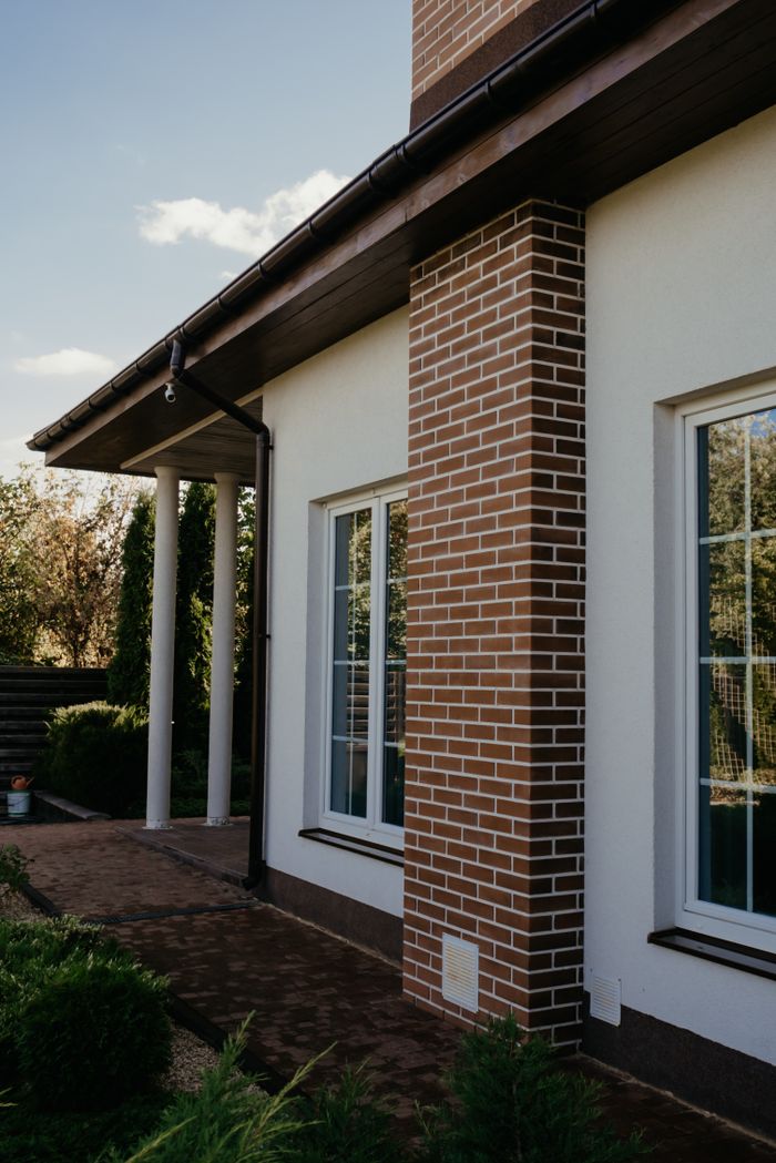 Charming modern house with brick features, glass windows, and lush garden.