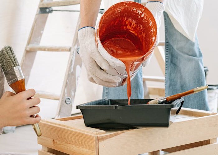 Close-up of people preparing paint and tools for a home renovation project indoors.