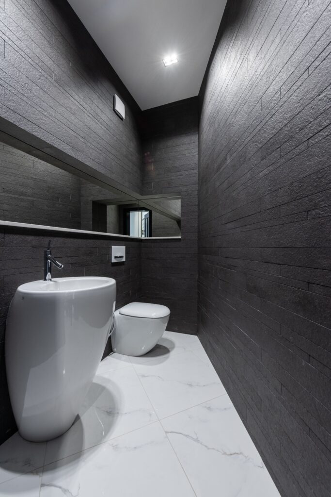 Interior of modern bathroom with creative white sink and toilet and dark gray walls