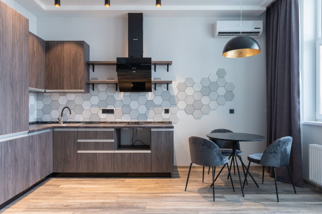 Creative design of cabinets and cupboards against table with chairs in contemporary kitchen with air conditioning on wall